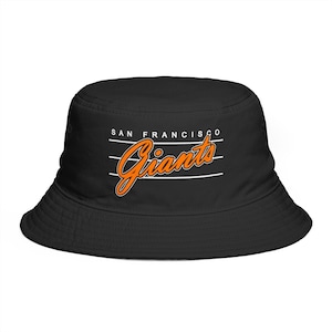 May include: Black bucket hat with the words "SAN FRANCISCO Giants" in white and orange lettering. The hat has a rounded crown and a downward-sloping brim. The hat is made of a soft, durable material.