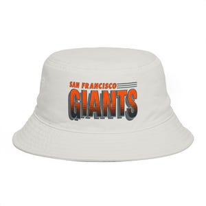 May include: White bucket hat featuring the text "SAN FRANCISCO GIANTS" in orange and black. The hat has a classic, casual design, perfect for sun protection or a fashion statement. The hat is made of a soft, durable material.