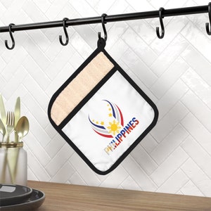 May include: White oven mitt with a black border and a design of the Philippine flag with the word "PHILIPPINES" underneath. The oven mitt is hanging on a black metal rack.