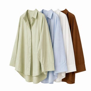 May include: Four button-down shirts in pastel colors: light green, light blue, white, and brown. Each shirt has long sleeves and a classic collar. The shirts are hanging, showcasing their design and fabric.
