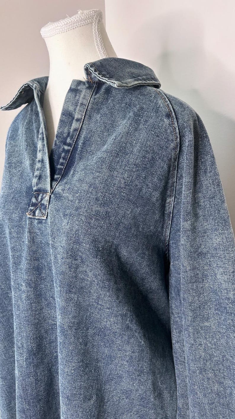 May include: A blue denim shirt with a collared neckline and long sleeves. The shirt has a slightly distressed look and a relaxed fit.