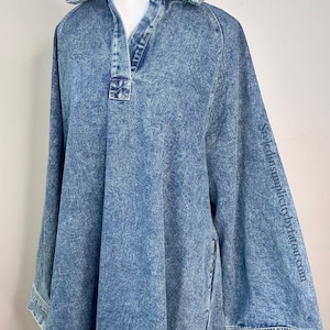May include: A long-sleeved denim dress with a collared neckline and a button closure. The dress has a relaxed fit and a slightly A-line silhouette. The fabric is a light blue wash with a subtle distressed look.