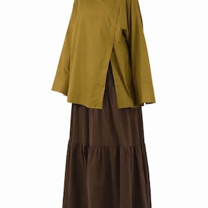 May include: A two-piece outfit featuring a long-sleeved, olive-green top with an asymmetrical front opening, paired with a tiered, floor-length brown skirt. The outfit is made of a soft, flowing fabric, ideal for a casual or semi-formal look.