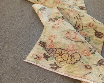 May include: A vintage-style rug with a floral pattern in shades of beige, pink, and brown. The rug is partially rolled up, revealing the underside. The design features faded floral motifs, giving it a distressed, antique appearance. The rug is suitable for home decor.