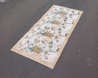Puede incluir: Una alfombra de pasillo beige con un patrón floral en tonos marrones, azules y rosas. La alfombra tiene un fondo crema con un borde beige.