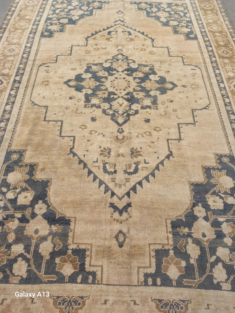 May include: A rectangular area rug with a central medallion design. The rug features a beige background with navy blue and brown geometric and floral patterns. The border has a repeating pattern in brown and beige.