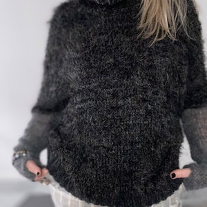 May include: A gray fuzzy turtleneck sweater with long sleeves and a high neckline.