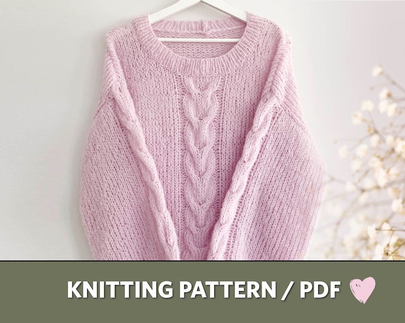 Puede incluir: Un su&eacute;ter de punto rosa claro con un dise&ntilde;o de punto trenzado en el centro y en las mangas. El su&eacute;ter est&aacute; colgado de una percha blanca. El texto "KNITTING PATTERN / PDF" est&aacute; en la parte inferior de la imagen.