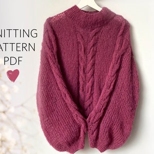 Può includere: Un modello di maglia PDF per un maglione rosa a treccia con collo alto.