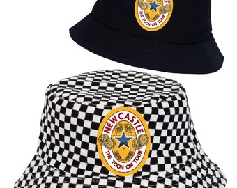 Puede incluir: Sombrero de cubo a cuadros blanco y negro con un parche de logotipo de cerveza New Castle amarillo y rojo que dice "The Toon On Tour".