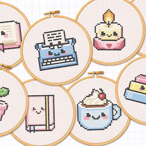 Pode incluir: Uma coleção de bastidores de bordado em ponto cruz com vários desenhos fofos. Os desenhos incluem um livro sorridente, uma máquina de escrever, uma vela, um tinteiro, uma planta em vaso, um caderno, uma xícara de café e livros empilhados.