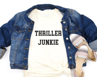 May include: A white t-shirt with the text "THRILLER JUNKIE" printed in black.