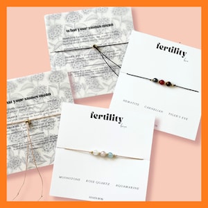 May include: An assortment of gemstone bracelets on cards. The cards feature the text "fertility here" and "what your stones mean". The bracelets include hematite, carnelian, tiger's eye, moonstone, rose quartz, and aquamarine.