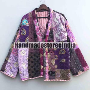 Könnte beinhalten: Patchwork-Jacke in Lila-, Rosa- und Brauntönen mit rot-weiß gestreiftem Futter. Die Jacke weist eine Vielzahl von Mustern auf, darunter Paisley- und Blumendesigns. Der Text "Handmadestoreeindia" ist auf der Vorderseite aufgedruckt.