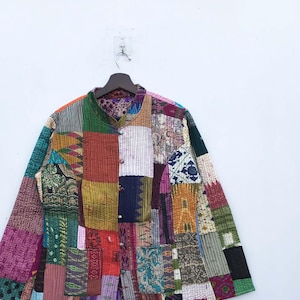 Könnte beinhalten: Eine bunte Patchworkjacke mit einem Mandarinkragen und Knopfverschluss. Die Jacke besteht aus verschiedenen Stoffen in verschiedenen Farben und Mustern, darunter Rot, Orange, Gelb, Grün, Blau, Lila und Braun.