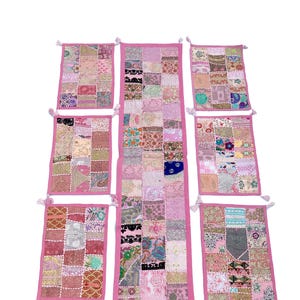 Könnte beinhalten: Sechsteiliges Set aus rosa Patchwork-Tischläufern und Platzsets mit Stickereien. Die Tischläufer und Platzsets bestehen aus verschiedenen Stoffen in Rosatönen, Beige und Weiß mit floralen und geometrischen Mustern. Die Kanten der Tischläufer und Platzsets sind mit einem rosa Rand verziert und haben Quasten.