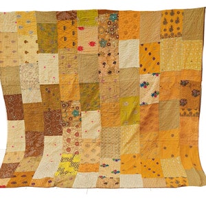 Könnte beinhalten: Eine Patchwork-Decke aus verschiedenen Gelb-, Braun- und Cremetönen. Die Decke besteht aus vielen Quadraten unterschiedlicher Größe und Muster, die ein einzigartiges und komplexes Design ergeben.