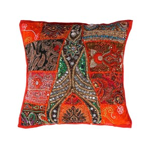 Könnte beinhalten: Quadratisches Zierkissen mit Patchwork-Design. Das Kissen zeigt eine lebendige Mischung aus roten, orangen und braunen Stoffen, verziert mit Perlen und Pailletten. Das zentrale Design ist ein symmetrisches Muster mit grünen und goldenen Akzenten, umrahmt von einem roten Rand. Ca. 40cm x 40cm.