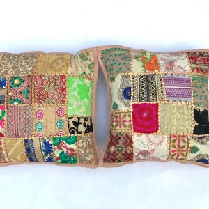 Könnte beinhalten: Zwei dekorative Kissen mit Patchwork-Muster. Die Kissen bestehen aus verschiedenen Stoffen in den Farben Rosa, Grün, Blau und Gold. Die Kissen sind mit aufwendigen Stickereien und Pailletten verziert.
