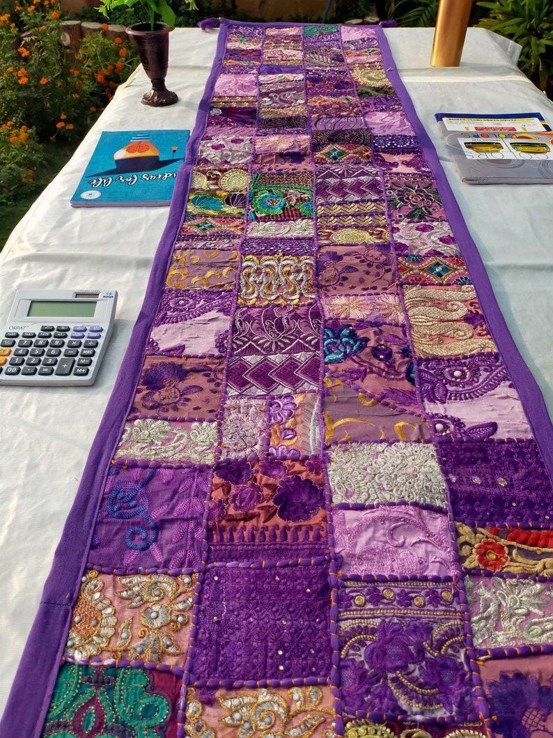 Peut inclure: Chemin de table patchwork rectangulaire dans diverses nuances de violet. Le chemin de table a une bordure violette unie et est fait de divers tissus &agrave; motifs. Le design comprend des &eacute;l&eacute;ments brod&eacute;s et textur&eacute;s, cr&eacute;ant une pi&egrave;ce d&eacute;corative.