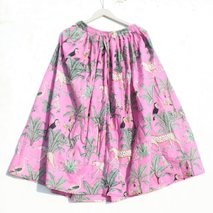 May include: A pink skirt with a jungle print featuring zebras, leopards, toucans, and palm trees.
