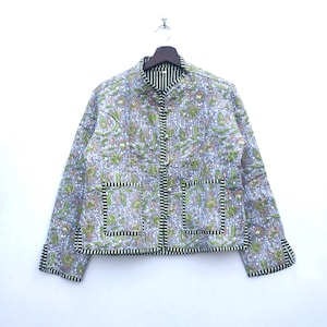 Peut inclure: Une veste matelassée blanche à imprimé floral et bordure verte. La veste a un col mandarin et une fermeture à bouton.