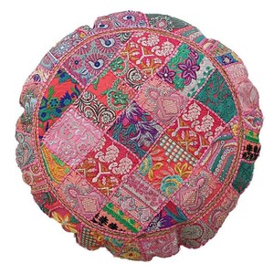 Op de afbeelding: Rond patchwork vloerkussen in een levendige mix van kleuren, waaronder roze, rood, groen en paars. Het kussen heeft ingewikkelde geborduurde details en een decoratieve rand. Het ontwerp is een mix van bloemen- en geometrische patronen.