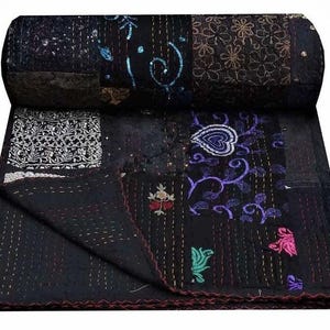 Könnte beinhalten: Eine schwarze Patchwork-Steppdecke mit verschiedenen gestickten Designs. Die Steppdecke hat oben einen aufgerollten Abschnitt, der die komplizierten Muster und Texturen zeigt. Das Design umfasst florale und abstrakte Motive in Lila-, Blau- und Rosatönen.