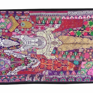 Könnte beinhalten: Ein lebendiges, rechteckiges Wandbehang mit schwarzem Rand. Das Patchwork-Design weist eine reiche Farbpalette auf, darunter Lila, Rot, Gold und Rosa. Auf dem Stoff befinden sich komplizierte Blumen- und geometrische Muster.