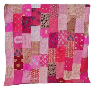 Könnte beinhalten: Eine Patchwork-Decke mit verschiedenen rosa, roten und braunen Stoffen. Die Decke besteht aus vielen verschiedenen Quadraten und Rechtecken, jedes mit einem einzigartigen Muster.