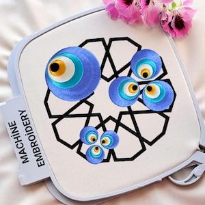 May include: Machine embroidery design featuring a geometric pattern with multiple blue evil eye charms. The design is on a white fabric hoop.