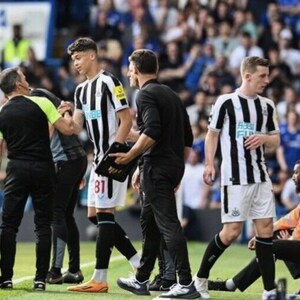 May include: A group of soccer players on a field, one player is being attended to by a medical professional. The players are wearing black and white striped jerseys with the text "Toon Army" on the front.
