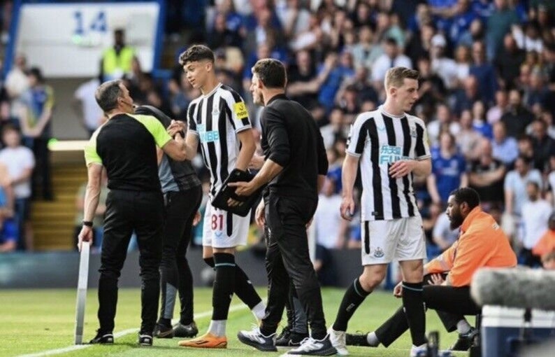 May include: A group of soccer players on a field, one player is being attended to by a medical professional. The players are wearing black and white striped jerseys with the text "Toon Army" on the front.