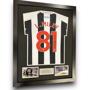 May include: A framed black and white soccer jersey with the number 81 and the name "L. Miley" on the back. The jersey is signed by the player. The frame includes three smaller photos of the player in action.