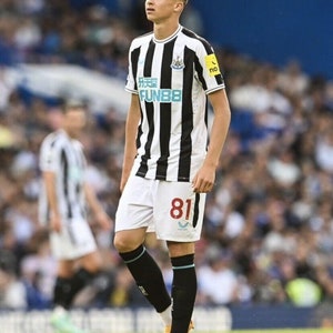 May include: A young soccer player wearing a black and white striped jersey with the number 81 on the back. The jersey has the text "FUN88" on the front. The player is wearing black socks and orange and black soccer cleats.