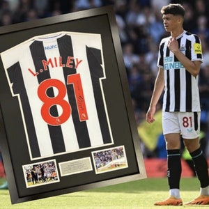 May include: A framed black and white soccer jersey with the name "L. Miley" and the number "81" on the back. The jersey is signed by the player. There are smaller photos of the player in the frame.