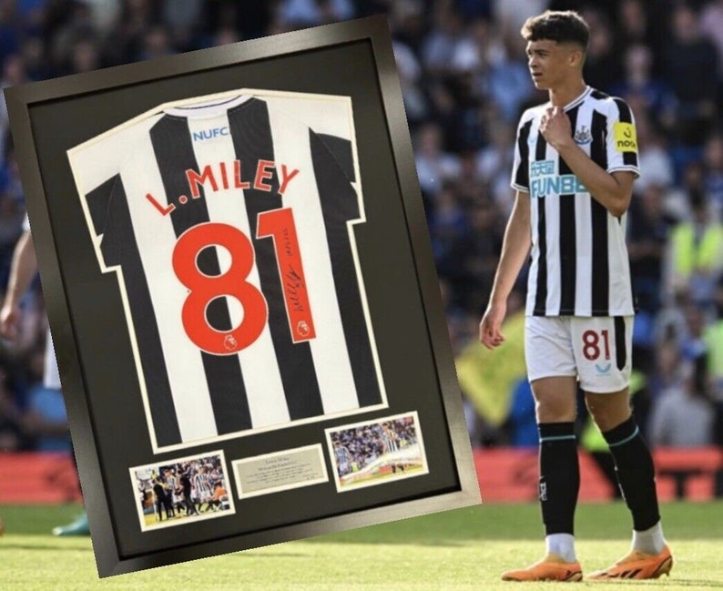 May include: A framed black and white soccer jersey with the name "L. Miley" and the number "81" on the back. The jersey is signed by the player. There are smaller photos of the player in the frame.