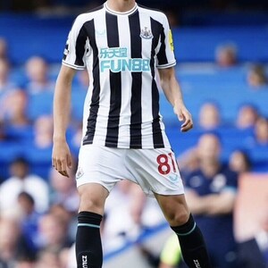 May include: A young soccer player wearing a black and white striped jersey with the text "FUN88" on the front. The player is wearing white shorts with the number 81 on the back. The player is wearing black shin guards and orange soccer cleats.