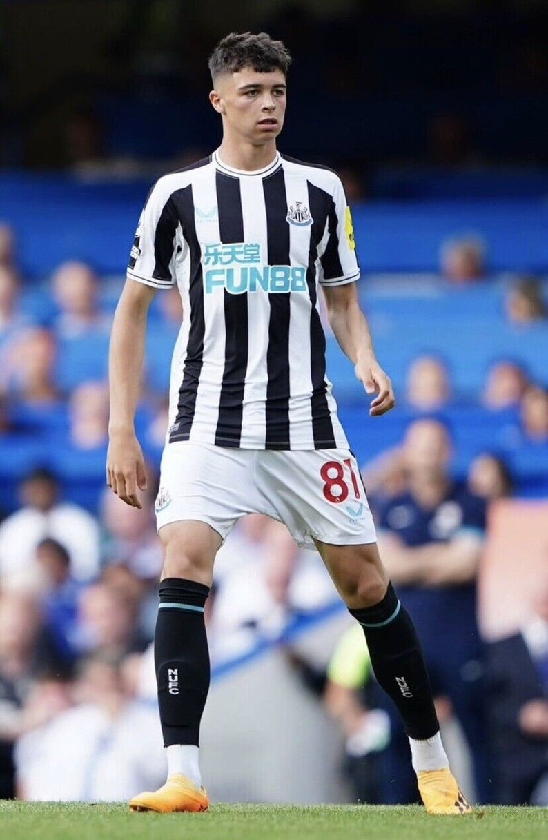 May include: A young soccer player wearing a black and white striped jersey with the text "FUN88" on the front. The player is wearing white shorts with the number 81 on the back. The player is wearing black shin guards and orange soccer cleats.