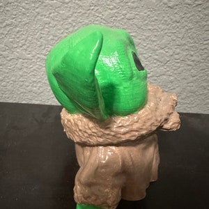 K&ouml;nnte beinhalten: Eine gr&uuml;ne und braune Figur eines Charakters aus dem Star Wars-Franchise. Der Charakter hat gro&szlig;e Ohren und tr&auml;gt einen braunen Mantel.