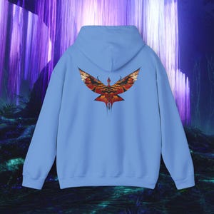 May include: A light blue hoodie with a detailed graphic of a stylized bird with outstretched wings in shades of red, orange, and gold. The design is centered on the back of the hooded sweatshirt.