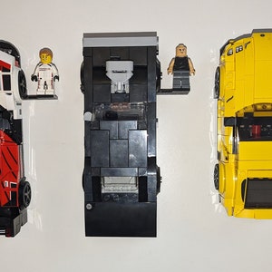 May include: Three Lego race cars, one black, one yellow, and one red and white with a Porsche logo. Two Lego figures are included, one wearing a racing suit and the other wearing a black shirt.