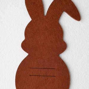 May include: Brown felt bunny rabbit cutout with two black lines drawn on the back.
