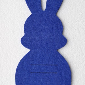 May include: A blue felt bunny cutout with two lines drawn on the body.