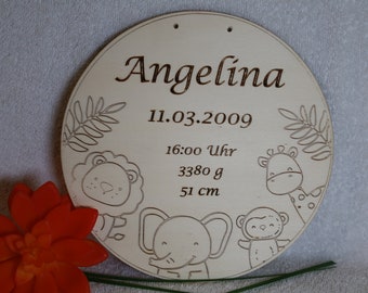 May include: A round wooden sign with the name "Angelina" and birth details. The sign includes the date 11.03.2009, time 16:00, weight 3380 g, and height 51 cm. It is decorated with animal illustrations.