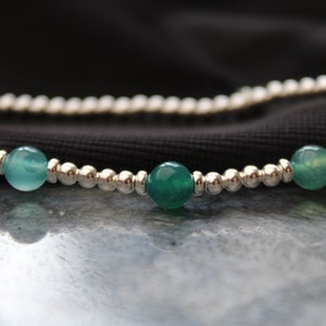 May include: A silver beaded bracelet with three green agate beads.