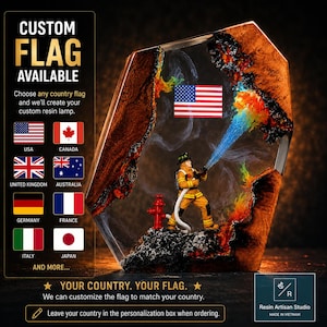 Puede incluir: Una lámpara de resina personalizada con una figura de bombero en equipo amarillo rociando un chorro de resina azul hacia un efecto de fuego naranja y rojo. La lámpara incluye una bandera estadounidense en miniatura y un marco de madera oscura.