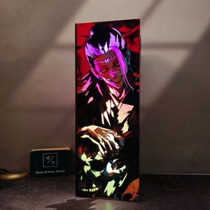 Puede incluir: Una pieza de arte de resina rectangular que presenta un personaje con cabello púrpura y una sonrisa siniestra, sobre un fondo rojo. La obra de arte brilla con colores neón, y la base tiene el texto "Resin Artisan Studio".