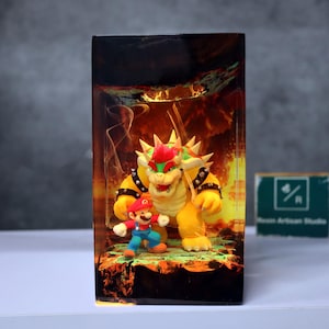 May include: A resin art piece featuring the characters Mario and Bowser from the Super Mario video game series. Bowser is yellow with spikes and Mario is wearing a red hat and blue overalls. The background depicts a fiery scene.