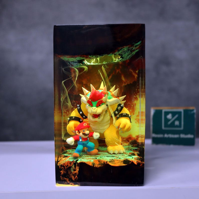 May include: A resin art piece featuring the characters Mario and Bowser from the Super Mario video game series. Bowser is yellow with a red mohawk, and Mario is in his classic red and blue outfit. The background has a fiery, glowing effect.